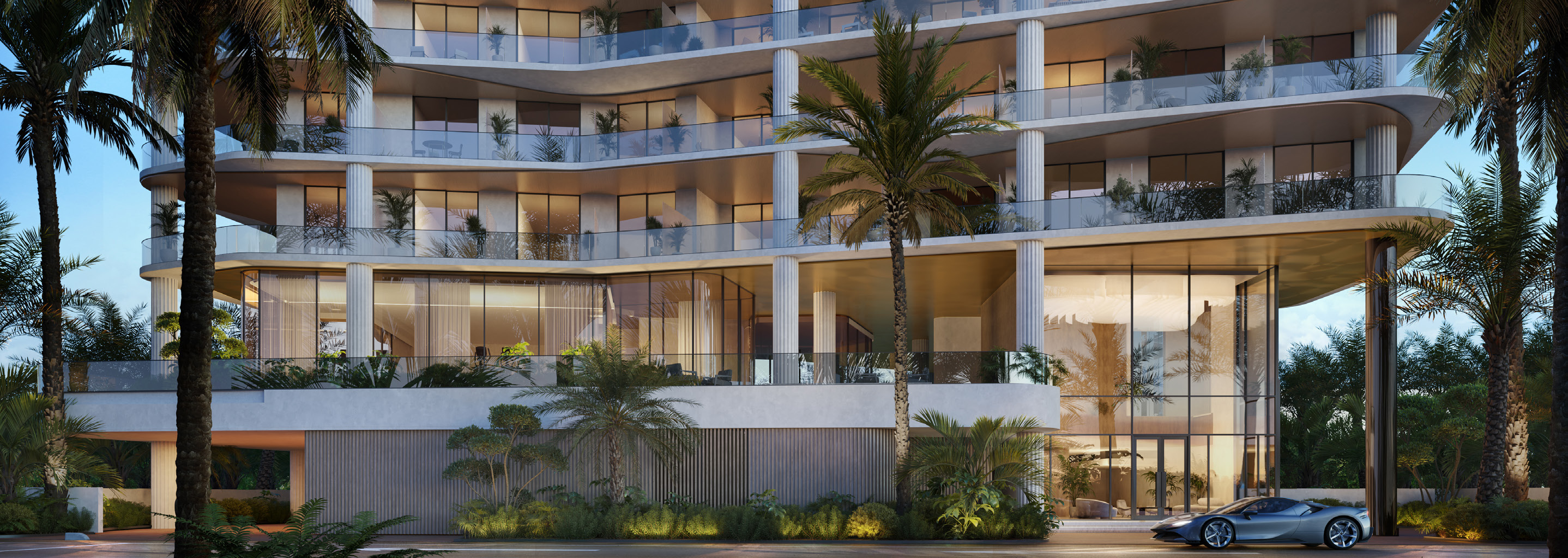 Curved glass façade and lush landscaped arrival of the residence at dusk